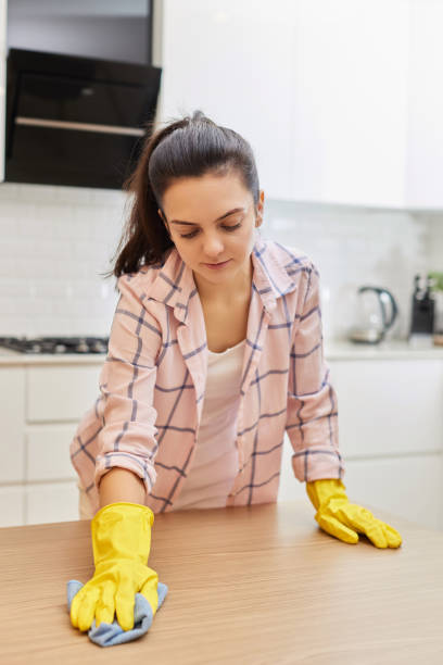 istock young woman cleaning wooden table with microfiber cloth. 1962770796