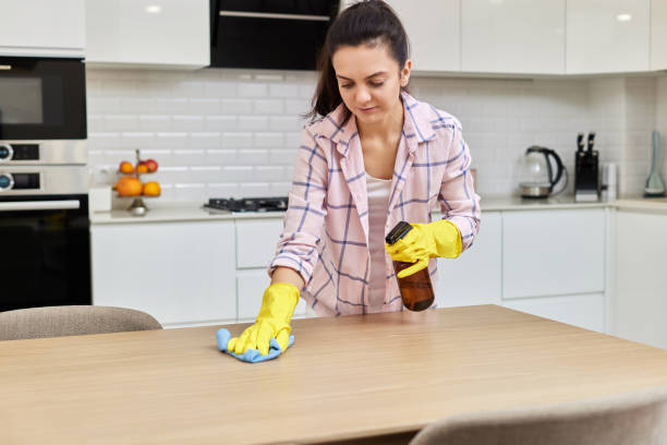 istock young woman cleaning wooden table with microfiber cloth. 1962771903