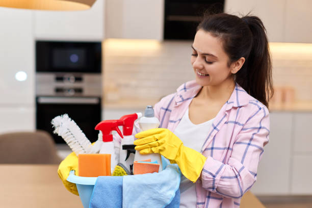 istock Woman in rubber gloves holding cleaning tools. 1962772426