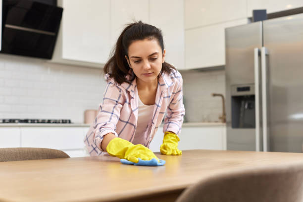istock young woman cleaning wooden table with microfiber cloth. 1962773010
