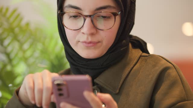 Hijab woman is texting a message at coffee shop.