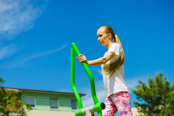 Woman making exercises on public equipment in city park. Girl working out in outdoor gym. Healthy lifestyle.
