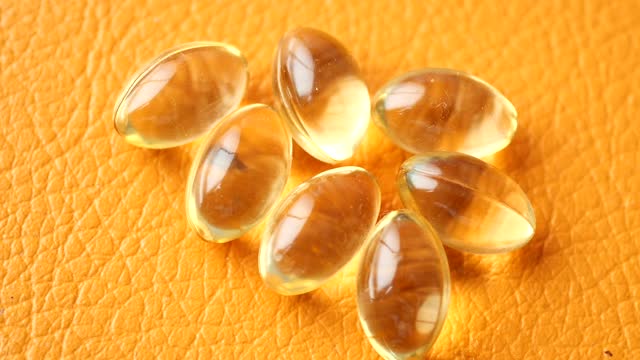 capsules from fish oil on orange color background