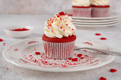 Red velvet cupcakes with cream cheese frosting and red sugar hearts. Delicious dessert for Valentines day. Selective focus, copy space