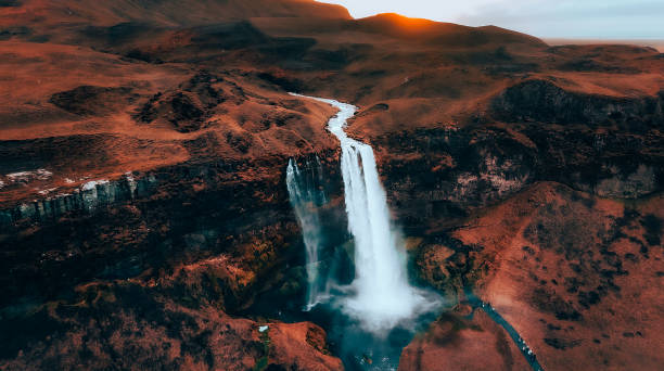 istock the sun is setting over the mountains and a waterfall with water 1962853944