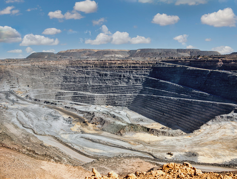 diamond mine open pit, panoramic view of the quarry layers, earth moving machines in the background