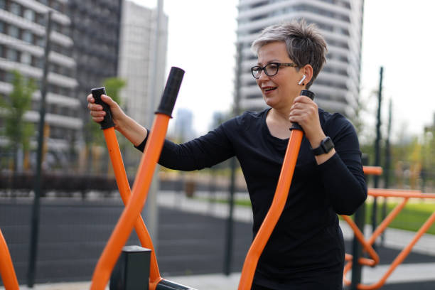 mulher feliz e madura gosta de fitness ao ar livre, irradiando saúde e alegria em um ambiente urbano. - aquecimento físico - fotografias e filmes do acervo