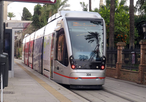 Modern orange tram stopped at a station in Athens, GreeceCaptured during soft evening light, the scene highlights contemporary public transport surrounded by greenery and city architecture. Ideal for travel content, urban mobility themes, and modern Athens lifestyle visuals.