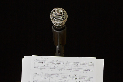 Microphone and sheet music are next to each other on a dark background