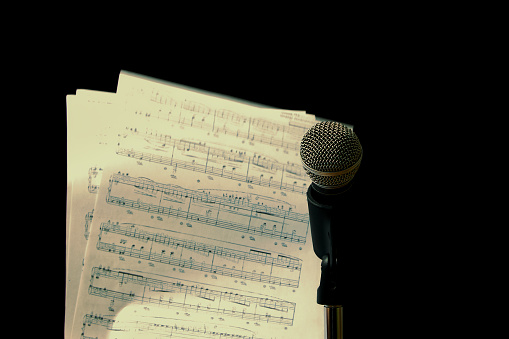 Microphone and sheet music side by side on dark background