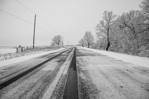 Snow-covered country road with trees in the background