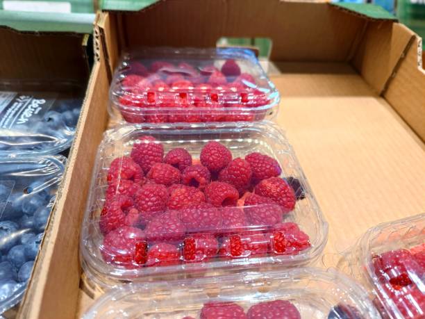 Raspberries in a plastic container packaging on a shelf in a supermarket in the fruit and vegetable department