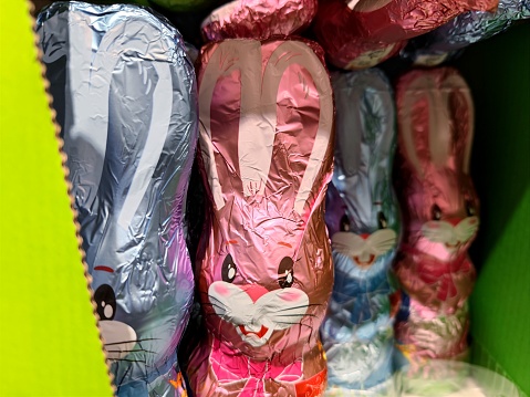 Chocolate Easter bunnies in pink and blue packaging are on supermarket shelves and are ready to be sold for Easter. There are no persons or trademarks in the shot.