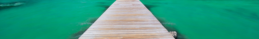 Wooden pier stretching over on green water - background image