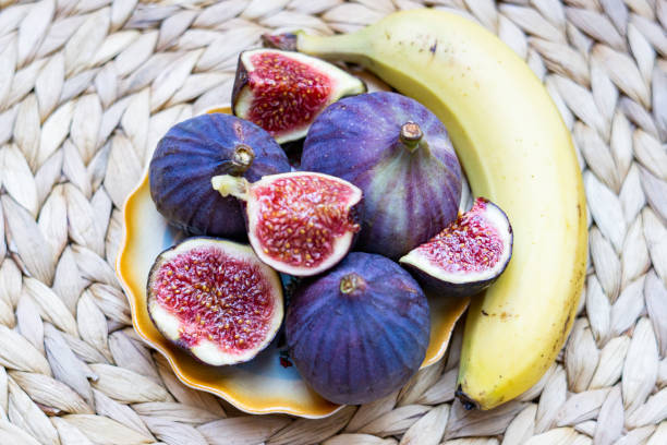 Still life of Fresh Figs lying on a plate with yellow edges, whole and cut into pieces