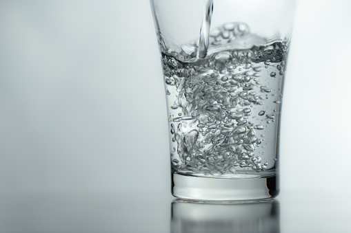 Filling a glass with water showing a drink concept. bubbles in fresh water with white background.