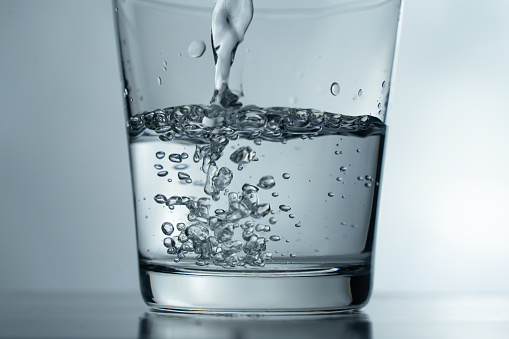 Filling a glass with water showing a drink concept. bubbles in fresh water with white background.