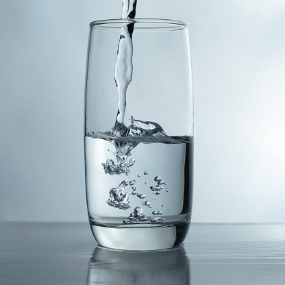 Filling a glass with water showing a drink concept. bubbles in fresh water with white background.
