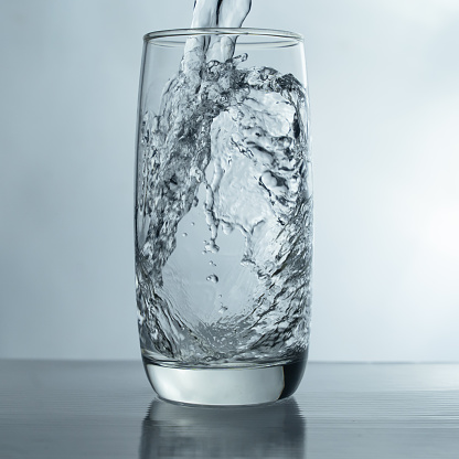 pouring water into glass on table, glass of water with splash isolated on white background. clean water for a good health. Mineral water in glass.