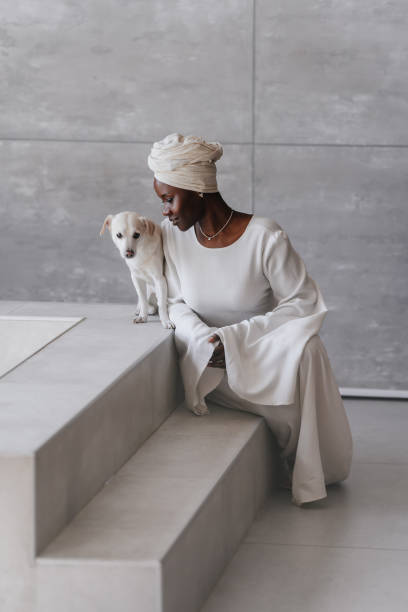 istock Elegant woman in white attire affectionately interacting with a white dog 1962947339