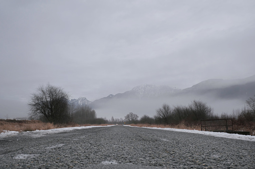 Looking down Rannie Road leading to the Grant Narrows Regional Park and Pitt River Dike during a snowy winter season in Pitt Meadows, British Columbia, Canada.