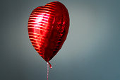Red Heart-shaped balloon on grey background
