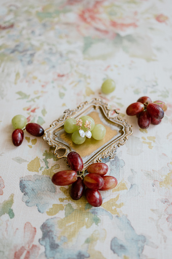 Some wedding earrings surrounded with grapes in a tray