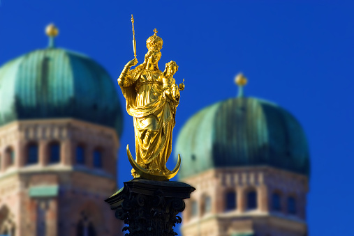 golden Statue of Virgin Mary with Jesus as a child, two towers of catholic church Liebfrauendom or Frauenkirche in background, Mary is the Patrona Bavariae, the Patron of Bavaria, Marienplatz, Munich, Bavaria, Germany, Europe