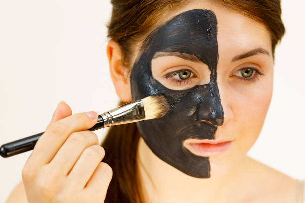 istock Female applying black mud facial mask 1963007937