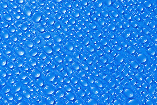 closeup, macro of many water drops, droplets, on a blue surface, background
