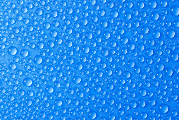 many small blue drops of water on a blue surface