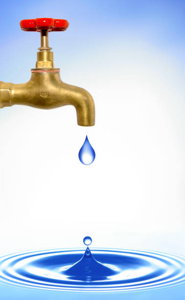 istock closeup of a golden brass water tap with red handle, water drop dripping off and causing circular waves on a water surface 1963020666