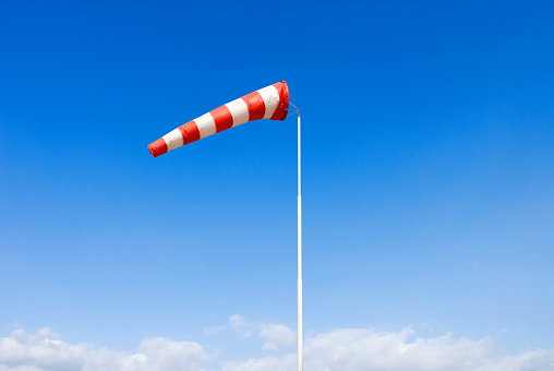 wind sock, wind drogue or wind sleeve, in blue sky, red and white indicating moderate wind