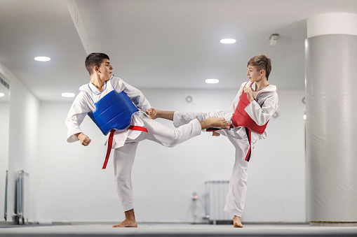 Taekwondo sporty boys are practicing kick and attack at martial art school.