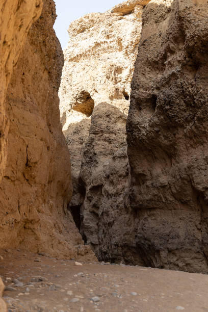 Narrow path between ember color canyon rocks under bright sunshine