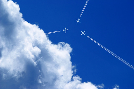 three aeroplanes with vapour trails in the blue sky fly exactly towards each other, collision