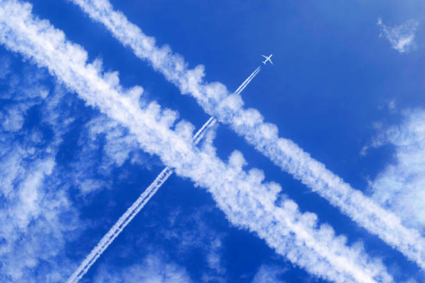 a passenger aircraft with contrails in the blue sky crosses other contrails