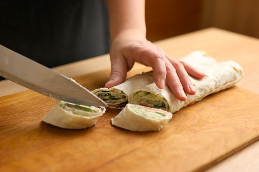 Wrapped in a roll pita bread is cut. Preparation of a roll with cheese, fish and vegetables