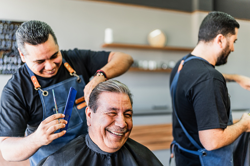 Barber cutting his customer hair at barber shop