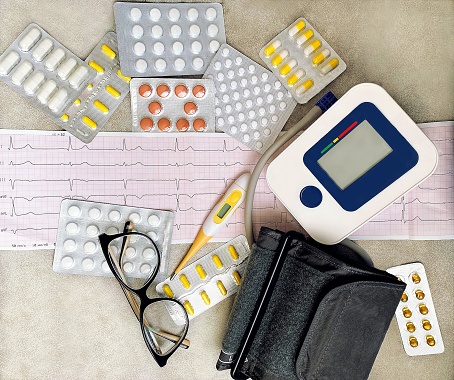 ward pill packs, tonometer, glasses and cardiogram are on a gray table