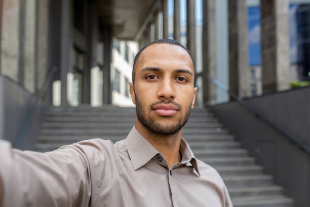 istock Confident young businessman taking a selfie while walking outside modern office building 1963091963