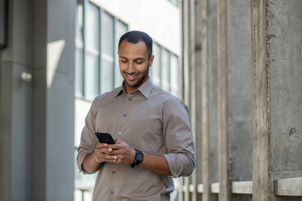 istock Confident young businessman using smartphone outside modern office building 1963091966