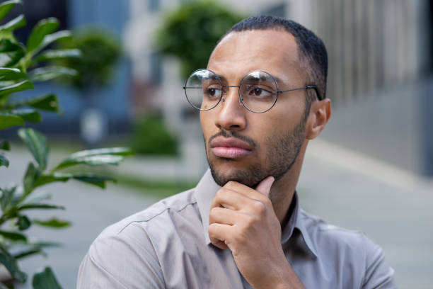 istock Contemplative young man with glasses looking away thoughtfully in an urban setting, embodying introspection 1963091994