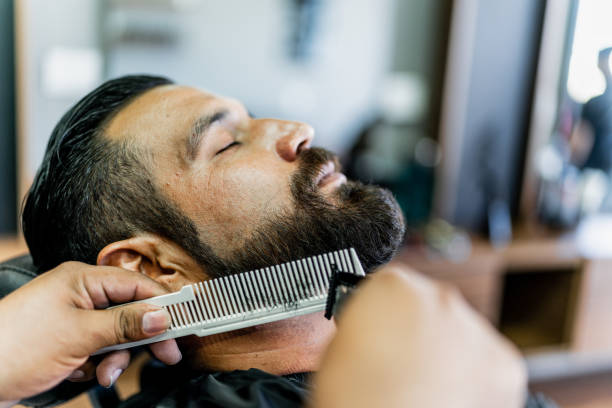 istock Mid adult man getting his beard cut at barber shop 1963116838