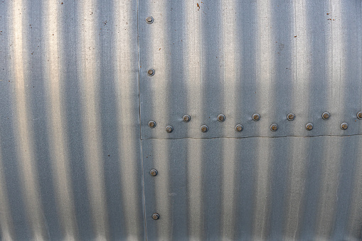 Close up of a corrugated steel plate with bolts and nuts