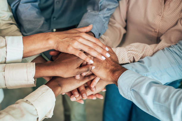 Teamwork Unrecognizable multi ethnic business team holding their hands together. Modern business team holding hands like successful team. hands clasped stock pictures, royalty-free photos & images