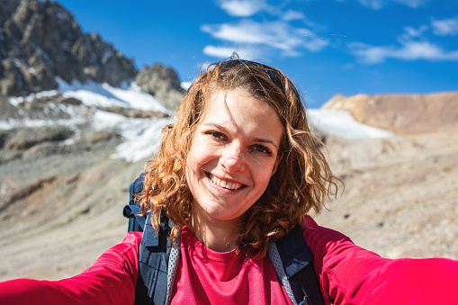 Smiling mid adult woman making selfie portrait while trekking in mountain