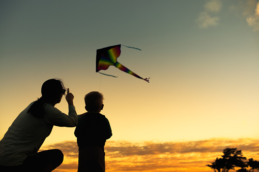 Father and son flying kite at sunset.