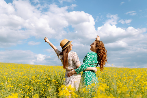 Two Beautiful women in the blooming field. Nature, vacation, relax and lifestyle. Summer landscape.