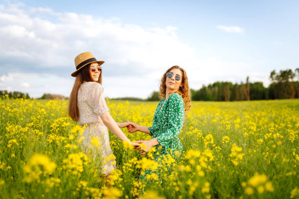 Two Beautiful women in the blooming field. Nature, vacation, relax and lifestyle. Summer landscape.